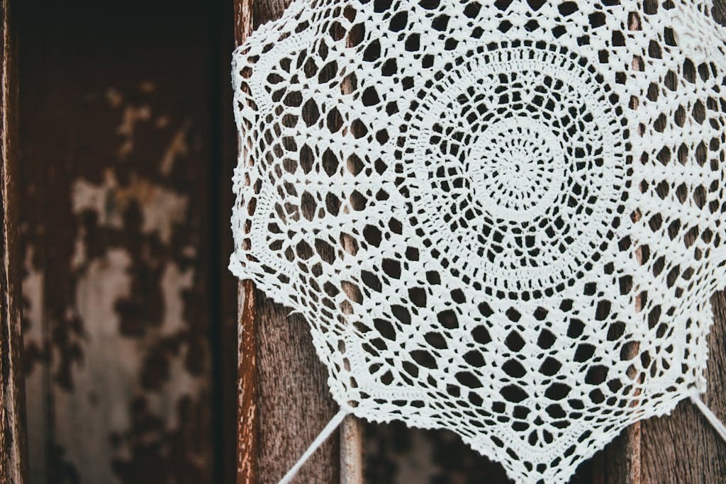 Delicate handmade crochet doily featuring an intricate design set against a rustic wooden background.
