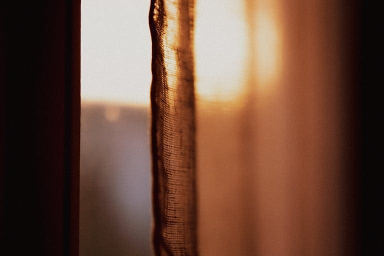 Sunlight streams softly through a sheer curtain, creating a warm, tranquil atmosphere.